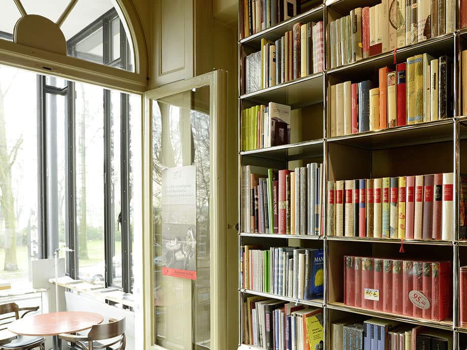 An der Wand steht ein Bücherregal. Im Hintergrund blickt man in den Erker, in dem ein Tisch mit Stühlen steht.© Gunter Glücklich