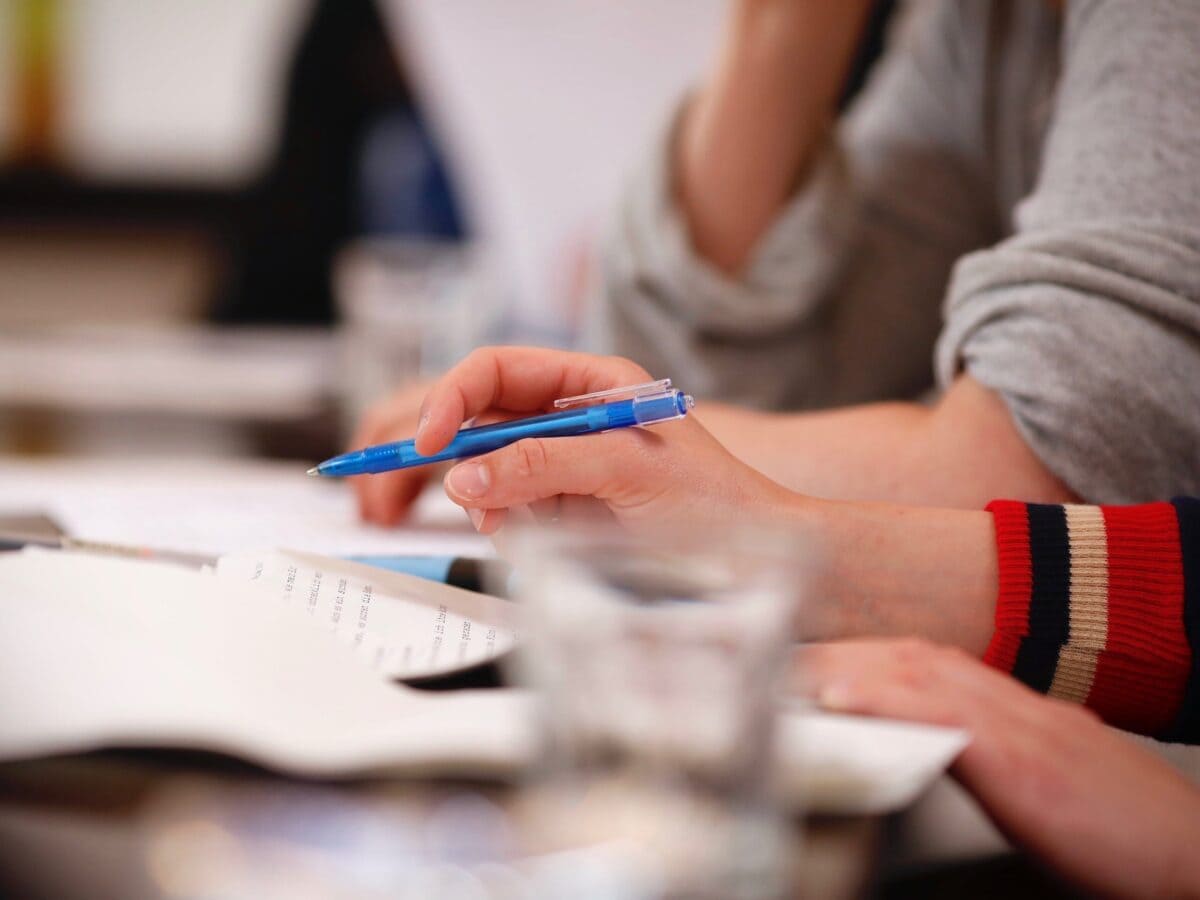 Close-Up von den Händen einer Person. Auf dem Tisch vor ihr liegen Papiere.© Sebastian Fuchs