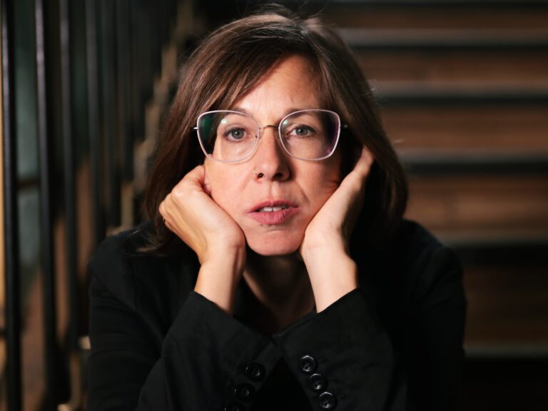 Doris Wirth sitzt auf einer Treppe und hat ihren Kopf in die Hände gestützt. Sie hat schulterlange braune Haare und trägt Brille sowie ein Nasenpiercing.Doris Wirth © Yousif Al-Chalabi