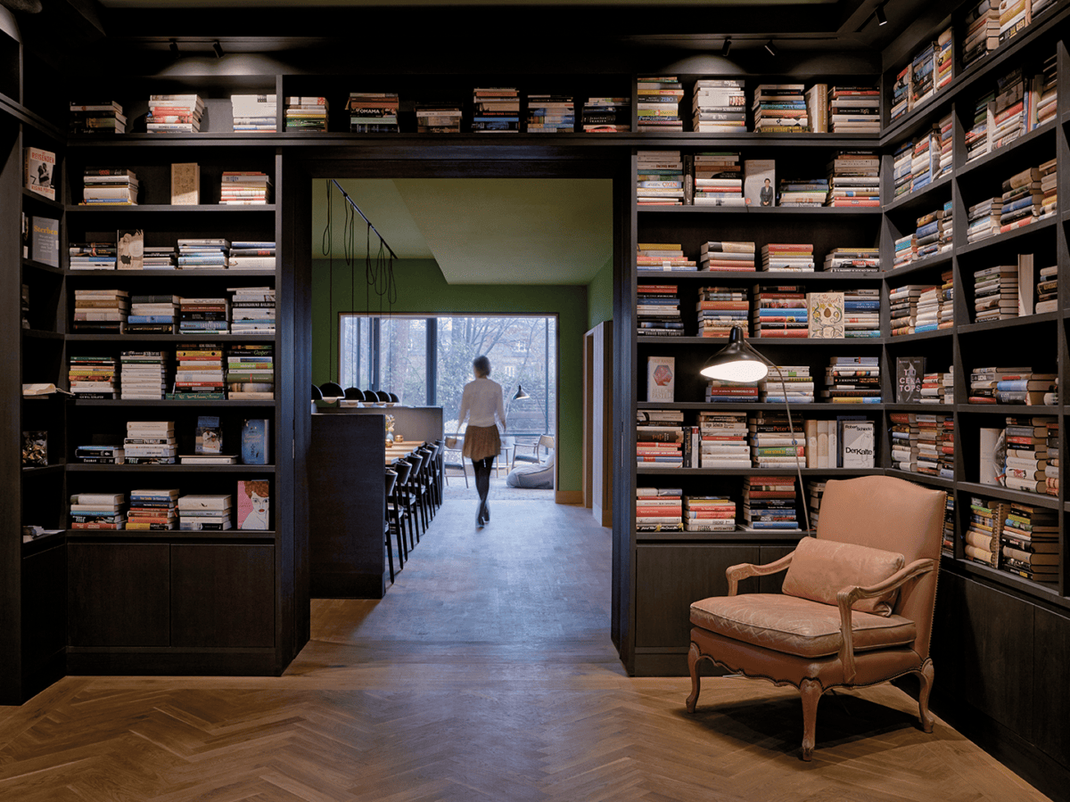 Blick auf ein großes und volles Bücherregal, das um einen Durchgang gebaut ist. Im Hintergrund sieht man eine Frau von hinten.© Hotel Wedina