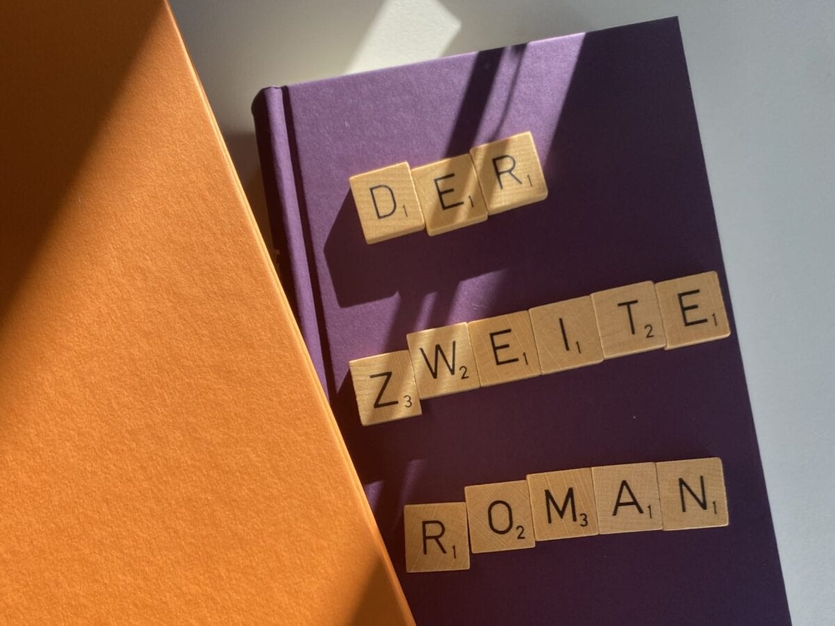 Auf einem Buch liegen Scrabble-Buchstaben, die »Der zweite Roman« bilden.