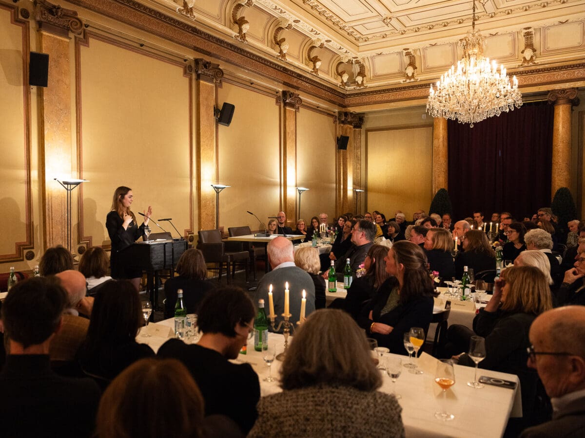 Feierlich hergerichteter Saal des Literaturhauses. Publikum blickt zur Bühne, wo Dana Vowinckel eine Rede hält.© Daniel Müller