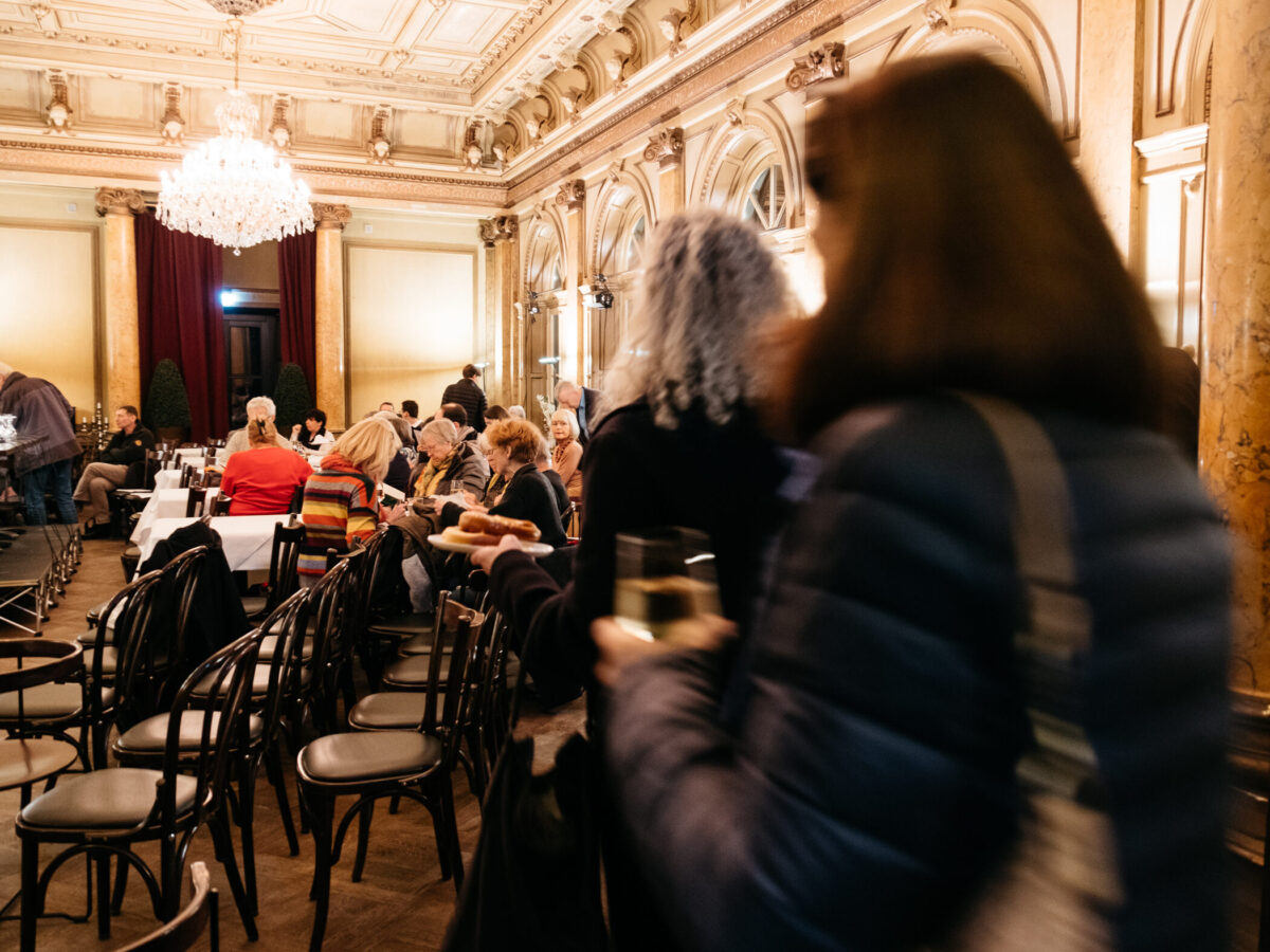 Personen gehen in den Eddy-Lübbert-Saal, in dem für eine Veranstaltung viele Stühle bereitstehen.© Kathrine Uldbæk Nielsen