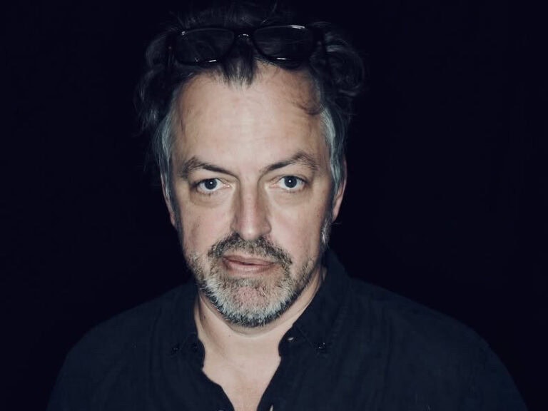 Nicolai von Schweder-Schreiner vor dunklem Hintergrund, er trägt Bart und eine Sonnenbrille im Haar© Stefan SchmidNicolai von Schweder-Schreiner © Stefan Schmid
