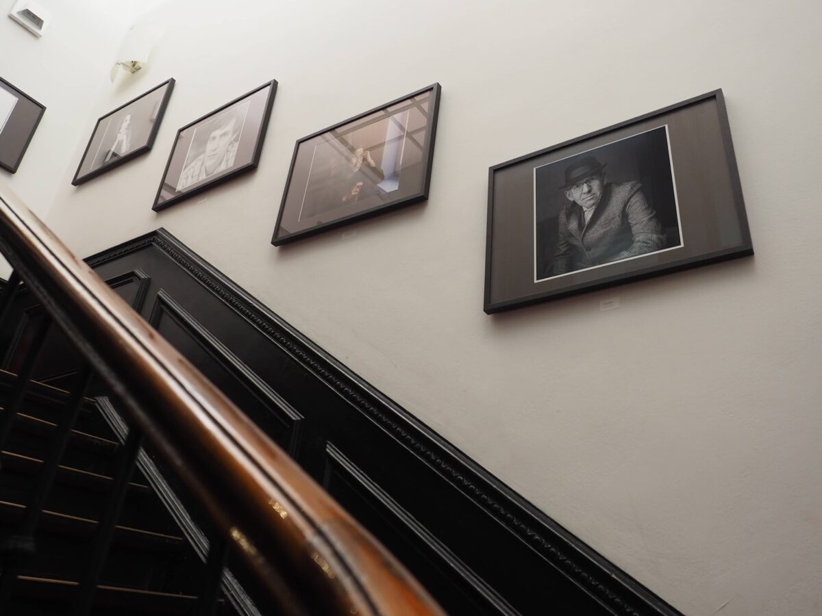 Das Treppenhaus des Literaturhauses: An der Wand hängen mehrere gerahmte Porträtfotografien.© Literaturhaus