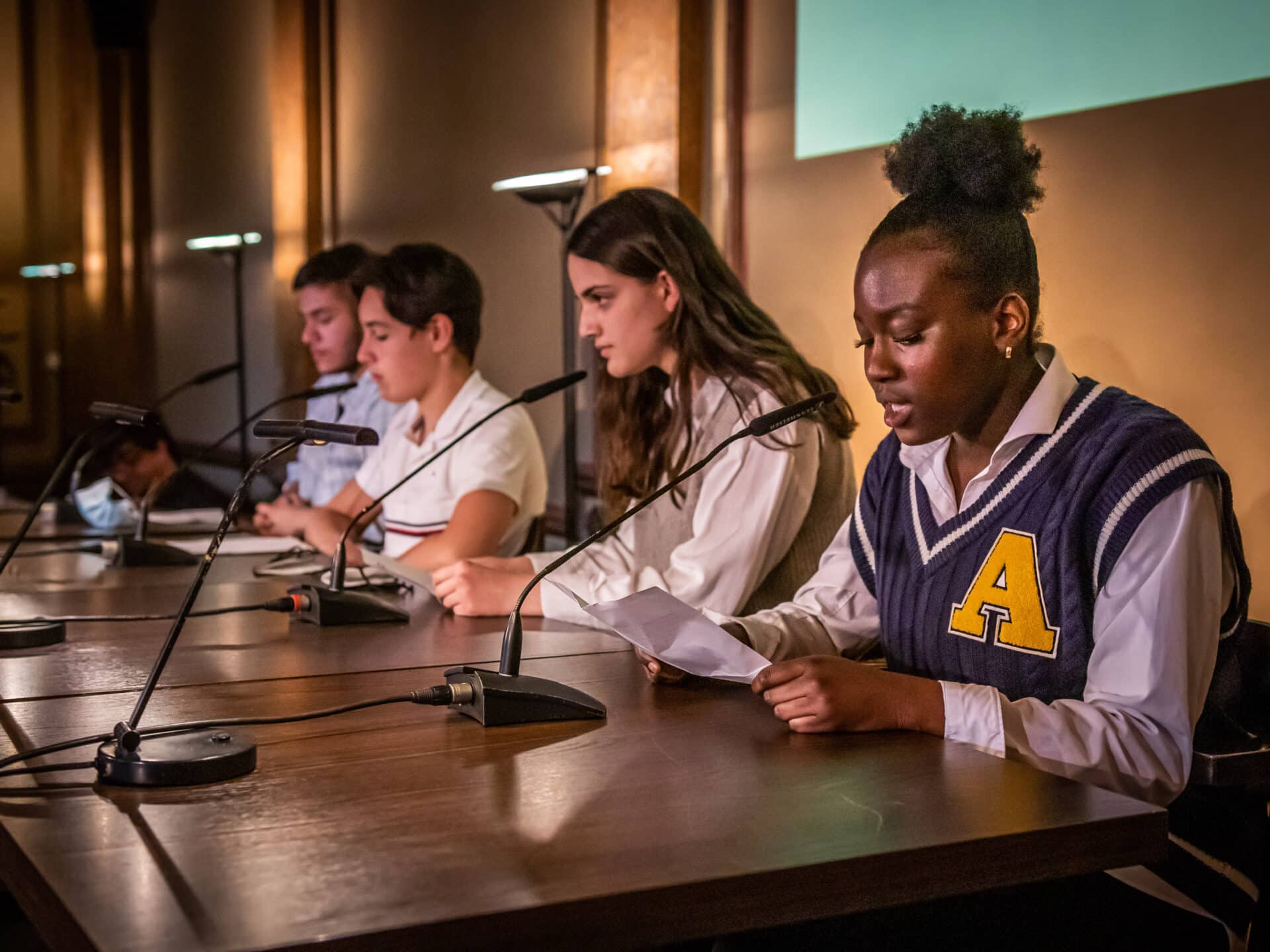 Vier Schüler:innen sitzen auf der Bühne des Literaturhauses. Sie halten Manuskripte in der Hand und vor ihnen stehen Mikrofone.© Nils Jaspersen