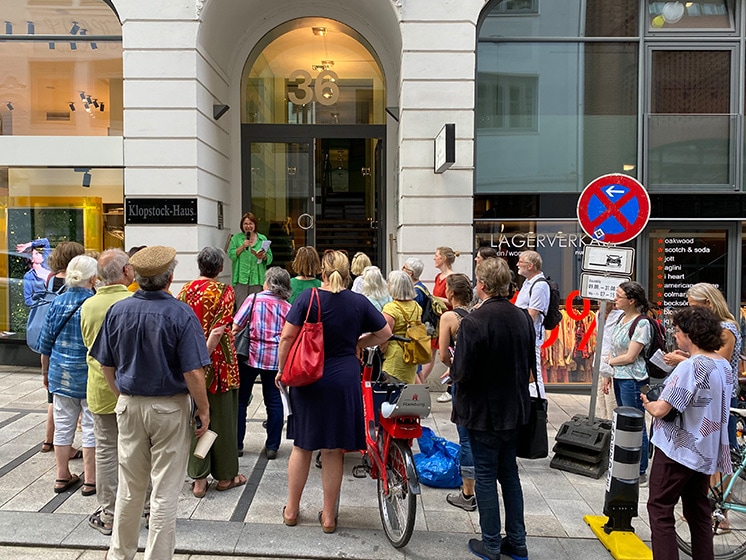 Ungefähr 20 Personen stehen vor dem Klopstock-Haus in Hamburg und hören einer vorlesenden Frau, Vera Rosenbusch, zu.© Literaturhaus